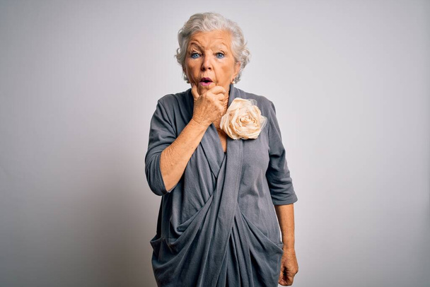 Senior beautiful grey-haired woman wearing casual dress standing over white background Looking fascinated with disbelief, surprise and amazed expression with hands on chin - Фото, зображення