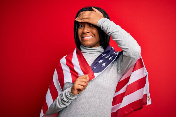 Молодая африканская патриотическая женщина, носящая флаг Соединенных Штатов Америки в день независимости, напряженная с поднятой головой, потрясенная стыдом и удивлением, сердитая и разочарованная. Страх и разочарование по ошибке
. - Фото, изображение