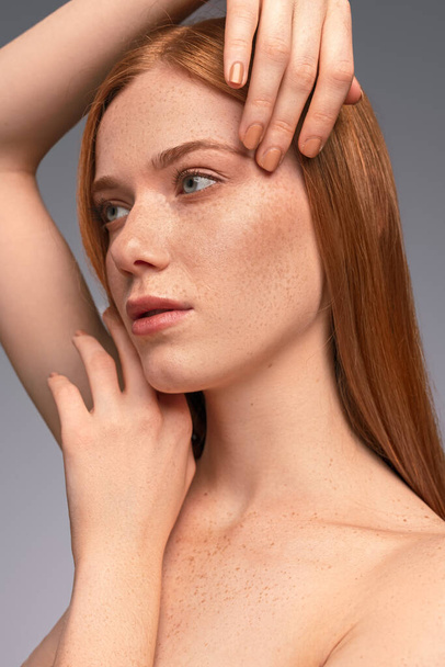 Freckled woman touching clean face - Фото, зображення