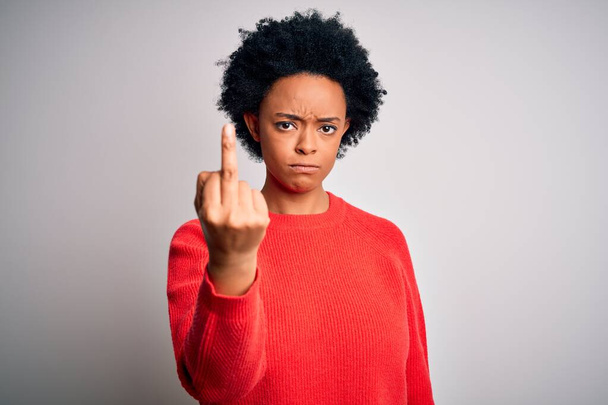 Молодая красивая афро-американка с вьющимися волосами в красном свитере демонстрирует средний палец, невежливое и грубое выражение лица
 - Фото, изображение