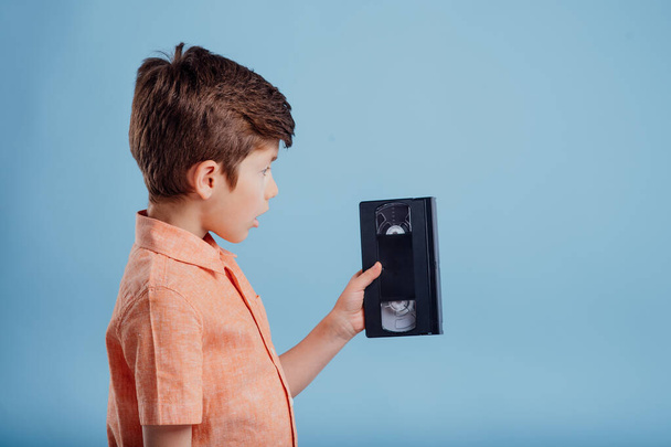 niño pequeño con cinta de vídeo, aislado sobre fondo azul
 - Foto, Imagen