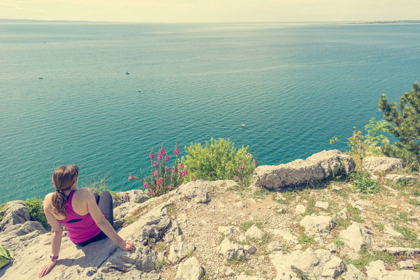 Aktiivinen nainen istuu ja nauttii merinäköalasta. Elävä elämä ja meditointi
. - Valokuva, kuva