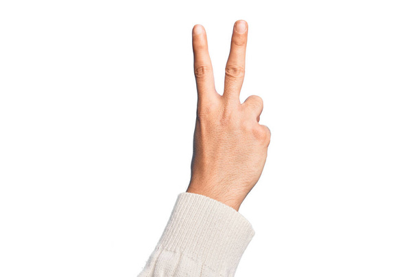 Beyaz arka planda parmaklarını gösteren beyaz tenli bir gencin eli iki parmağını gösteriyor, işaret ediyor zafer ve kazanan sembol. - Fotoğraf, Görsel