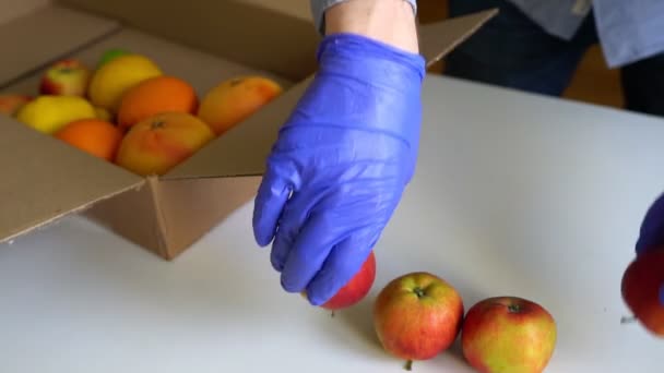 Добровольцы в защитных медицинских перчатках и фруктах в коробке для пожертвований
. - Кадры, видео