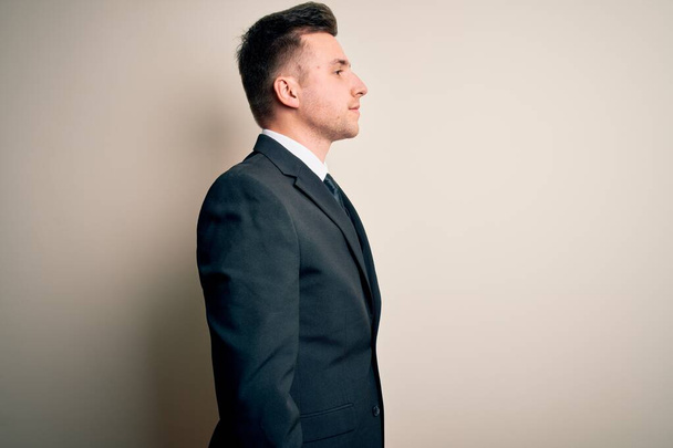 Fiatal jóképű üzletember visel elegáns öltöny és nyakkendő felett elszigetelt háttér keres oldalra, pihenjen profil pózol természetes arc és magabiztos mosoly. - Fotó, kép