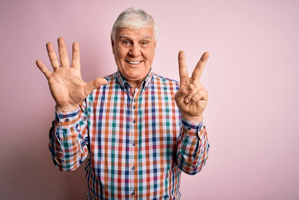 Senior bonito hoary homem vestindo camisa colorida casual sobre isolado fundo rosa mostrando e apontando para cima com os dedos número sete, enquanto sorrindo confiante e feliz
. - Foto, Imagem