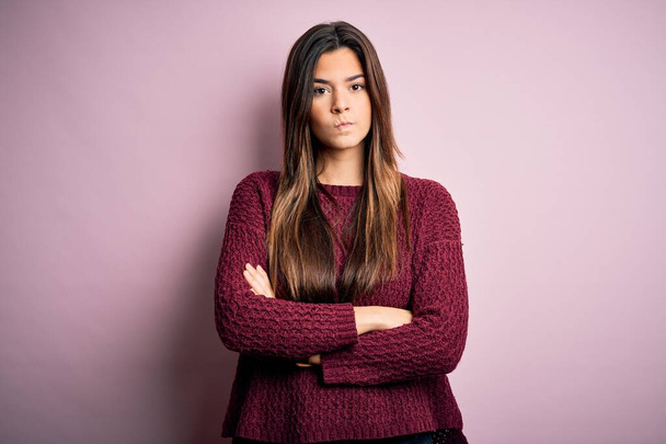 Young beautiful girl wearing casual sweater over isolated pink background skeptic and nervous, disapproving expression on face with crossed arms. Negative person. - Zdjęcie, obraz
