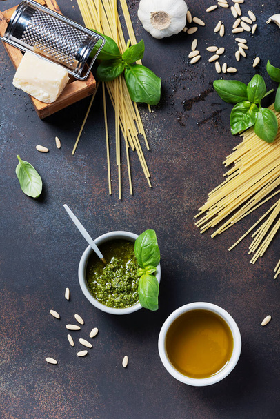 Condiments for cooking italian pasta: spaghatti, basil, olive oil, garlic and pine nuts on the black table. Top view image with a copy sppace - Foto, afbeelding