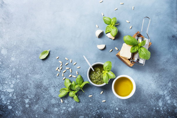 Fresh Italian pesto with basil, pine nuts, cheese and oil on the blue background. Top view image with a copy space - Foto, imagen