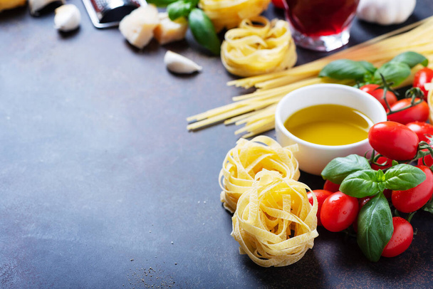 Spaghetti, tagliatelle, tomato, basil, cheese, garlic and wine on the black background. Concept of a healthy Italian cooking - Foto, Imagen