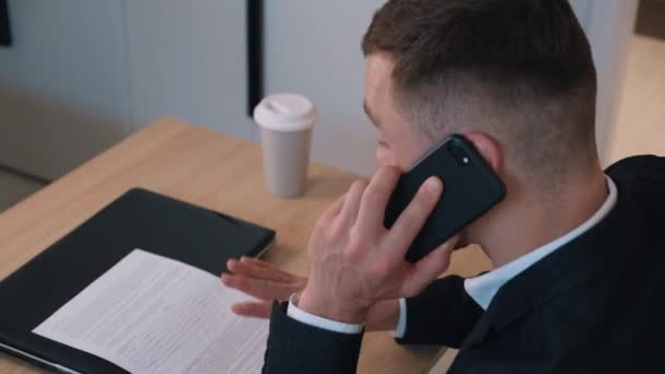 Positive entrepreneur businessman talking mobile phone emotionally at home office. Business discussion by phone, workflow. - Felvétel, videó