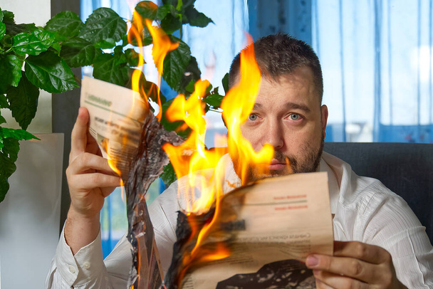 Un uomo che legge notizie su giornali in fiamme. Rivista in fiamme, giornale in mano a Mae. fake news, ultime notizie concetto
 - Foto, immagini