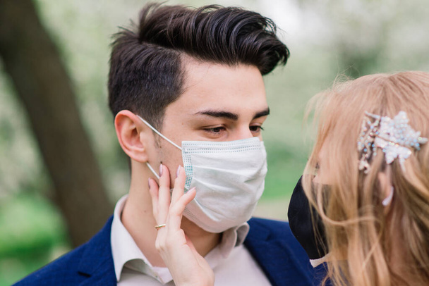 Düğün günlerinde karantina sırasında parkta maske takan genç bir çift. Coronavirus, hastalık, koruma, hastalık. Avrupa kutlamaları iptal edildi. - Fotoğraf, Görsel