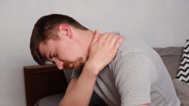 Zijaanzicht van overstuur vermoeide jongeman dragen t-shirt voelt pijn in de nek in de ochtend na het slapen, wakker in slecht humeur met pijnlijke plotselinge pijn of stijfheid. Fibromyalgie-concept - Video