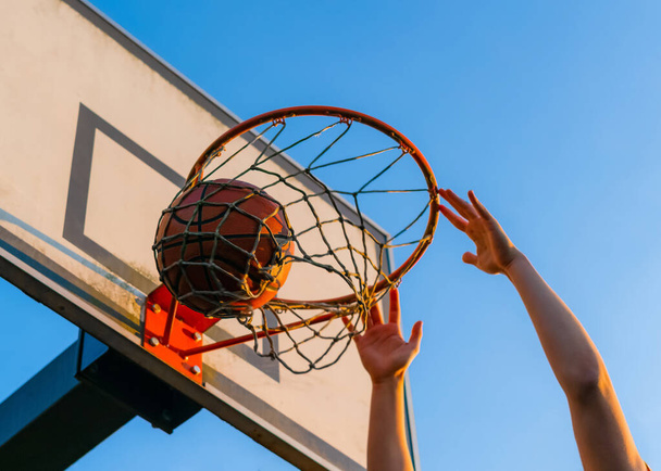 Pouliční basketbalová soutěž. Zblízka míček padá do koše. Městská hra mládeže. Koncept úspěchu, bodování bodů a vítězství - Fotografie, Obrázek