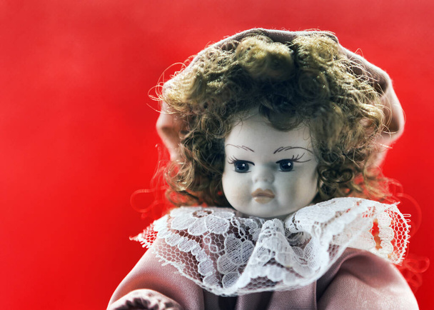 Schönes Porzellan Brünette Puppe Porträt mit Vintage-Kleid und lockigen Haaren und nachdenklichen Blick - Foto, Bild
