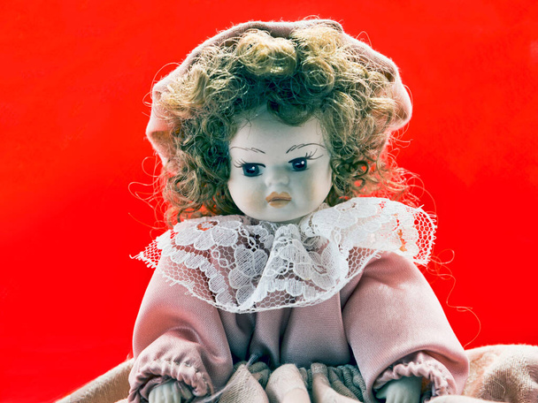 Όμορφη πορσελάνη μελαχρινή κούκλα πορτρέτο με vintage φόρεμα και σγουρές τρίχες και στοχαστική εμφάνιση - Φωτογραφία, εικόνα