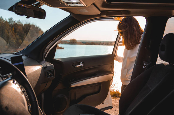 A nők napnyugtakor szállnak ki a kocsiból. Megállt a tó mellett. az utazás koncepciója - Fotó, kép