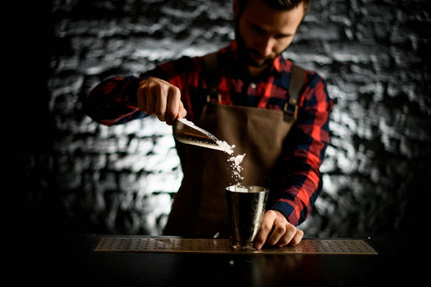 male bartender pours ice into metal glass - Foto, imagen