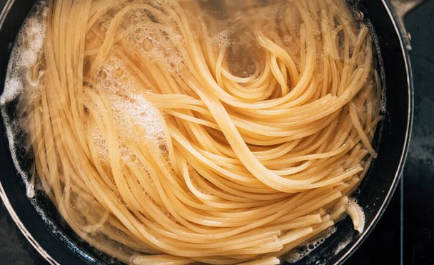 Close-up van spaghetti pasta In kokend heet water in stalen pan. Voorbereiding voor het maken van Al Dente Spaghetti. - Foto, afbeelding