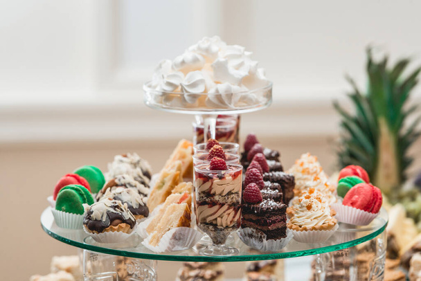 suporte de vidro com cupcakes e outros doces em uma mesa de bar de doces de casamento
. - Foto, Imagem