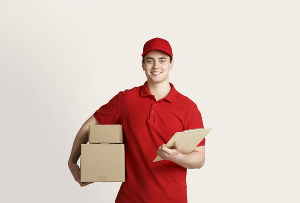 Home delivery with courier. Delivery man holds cardboard boxes and tablet - Photo, Image