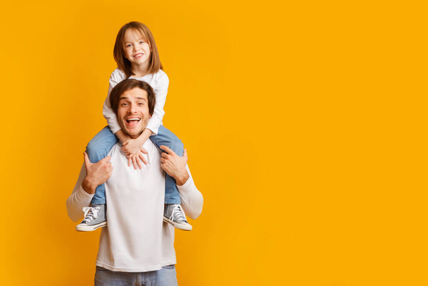 Красивый отец несет свою веселую маленькую дочь на плечах
 - Фото, изображение