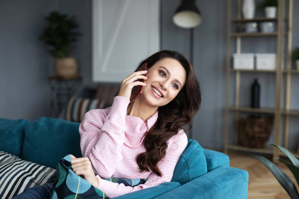 Beautiful woman smiling and looking to the side, while talking by phone at home. - Fotoğraf, Görsel