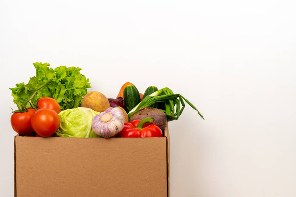 Fresh vegetables in a cardboard box on a white background. Fresh and healthy food delivery concept. Space for text. - Foto, afbeelding