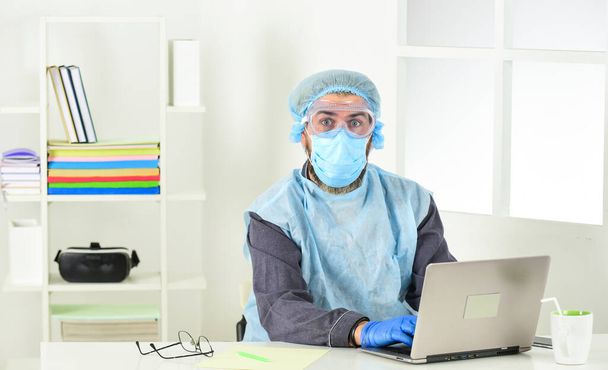 Employees who may be at risk of being exposed to coronavirus. Home office. Remote job. Worker in protective equipment. Totally protected. Wearing mask protect from coronavirus. Serious hygiene - Fotoğraf, Görsel
