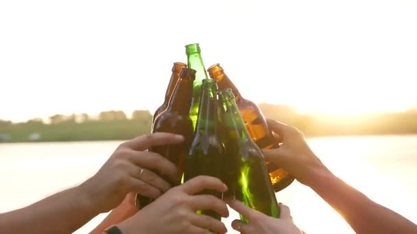 Група багатоетнічних молодих людей готує тости з пляшками пива і танцює до музики на заході сонця, друзі п'ють пиво на заході сонця
 - Кадри, відео