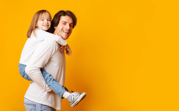 Sonriente papá y niña posando sobre fondo amarillo
 - Foto, imagen