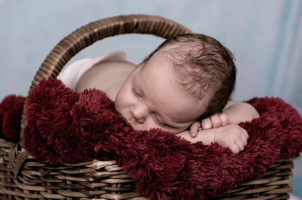Fröhliches Neugeborenes schläft im Weidenkorb - Foto, Bild
