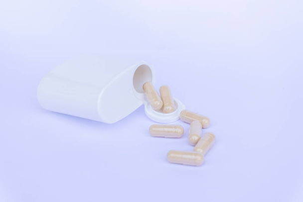 Lääketieteelliset pillerit tai kapselit valuvat valkoisesta lääkelaatikosta kevyellä taustalla. Kopioi tilaa logollesi laatikossa tai taustalla
. - Valokuva, kuva