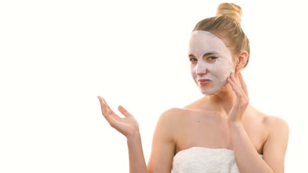 La mujer con una máscara facial limpia haciendo gestos sobre el fondo blanco. cámara lenta
 - Imágenes, Vídeo