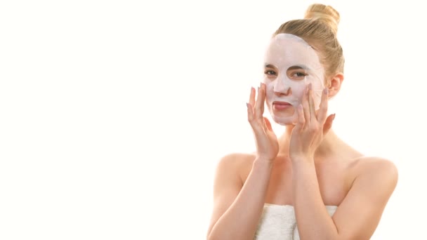 Žena s čistou obličejovou maskou ukazuje na bílé pozadí - Záběry, video