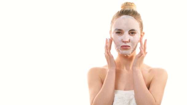 La mujer linda con una máscara limpia tocando la cara en el fondo blanco
 - Metraje, vídeo