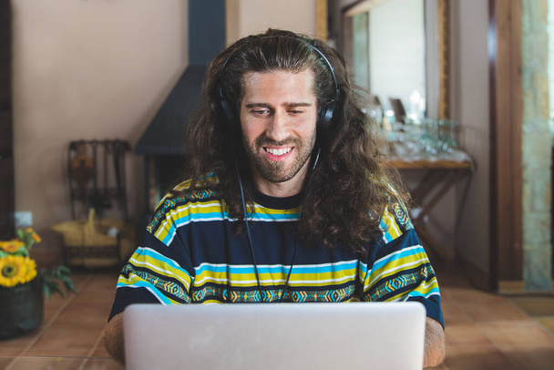 jonge man met een laptop werken en video bellen vanuit huis - Foto, afbeelding