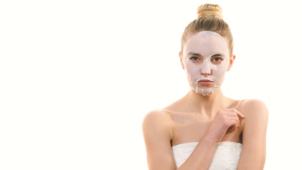 Roztomilá žena s čistou obličejovou maskou flirtuje na bílém pozadí - Záběry, video
