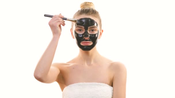 Šťastná žena nanášení péče o pleť masku obličeje na bílém pozadí - Záběry, video