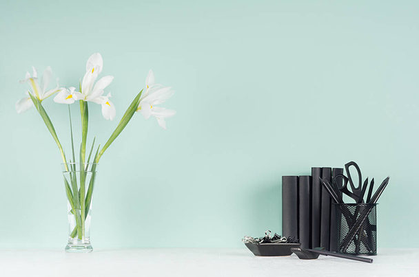 Spring green mint menthe interior of office with black stationery, books, fresh white iris bouquet  in transparent glass vase on soft light white wood board, copy space. - Fotografie, Obrázek