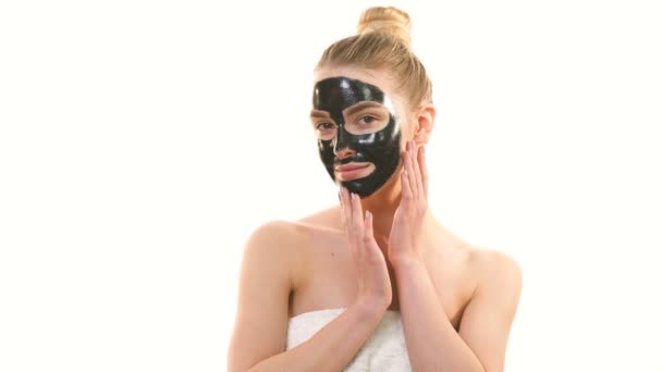 The happy woman with a black mask touching a face on the white background - Imágenes, Vídeo