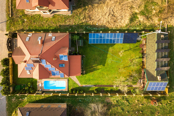 Vista aérea de uma casa privada com jardim coberto de grama verde, painéis solares no telhado, piscina com água azul e gerador de turbinas eólicas. - Foto, Imagem