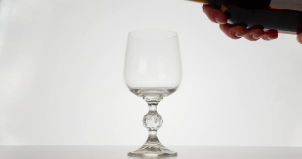 Close-up shot. The red wine is pouring into a glass. White background. 4K - Πλάνα, βίντεο
