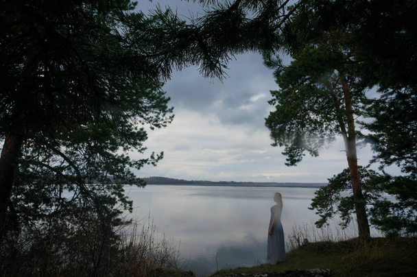 Silhouette woman standing alone on sea coastunder pine tree. travel destination . summer vacation. - Фото, изображение