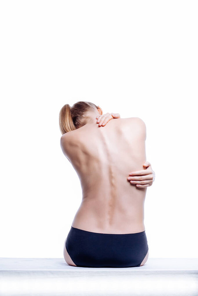 Schöner athletischer Frauenkörper. Rückenschmerzen. Nackte Frau in kurzen Hosen. Studioaufnahme der Rückseite, isoliert auf weißem Hintergrund. - Foto, Bild