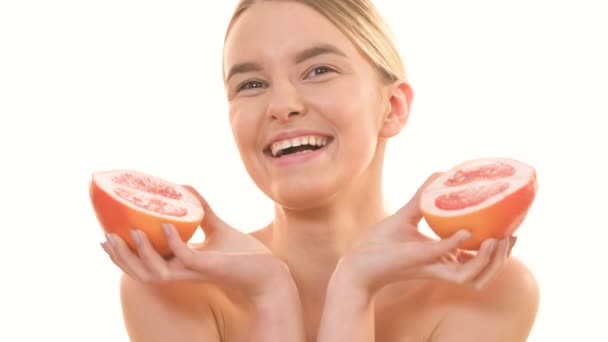 A gyönyörű nő kezében két fél grapefruit a fehér háttér - Felvétel, videó