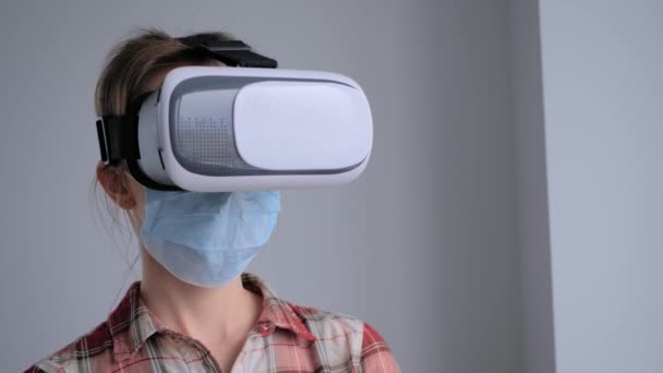 Mujer joven con máscara facial médica y auriculares de realidad virtual - Concepto VR - Metraje, vídeo