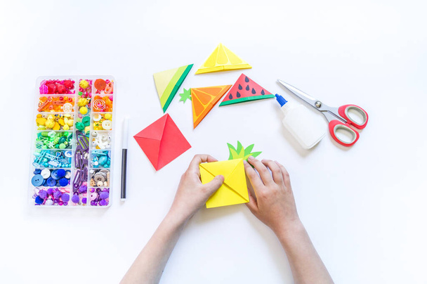 Bookmark for a child book to school. Origami paper craft with children's hands. Summer fruit tropics. - 写真・画像