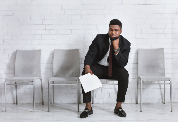 Giovane uomo di colore si sente esausto di aspettare il suo colloquio di lavoro in ufficio. Spazio vuoto
 - Foto, immagini